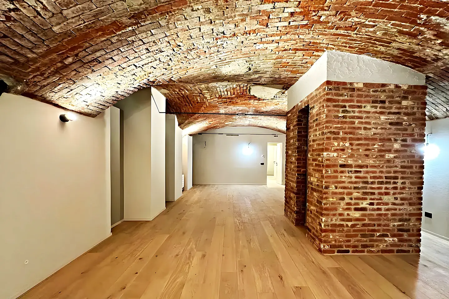 Sala con bóveda catalana de ladrillo visto restaurada y suelo de madera en una finca de Vilanova i la Geltrú