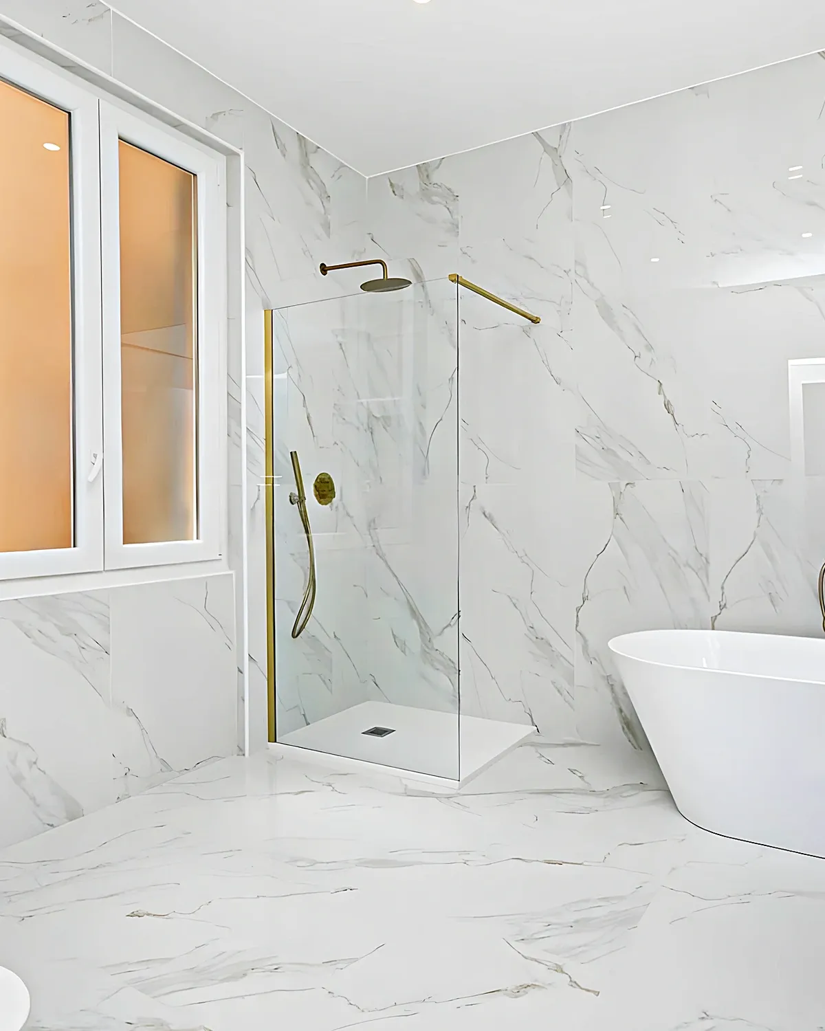 Baño con bañera exenta, mármol calacatta y grifería dorada en una casa de Ribes Roges, Vilanova