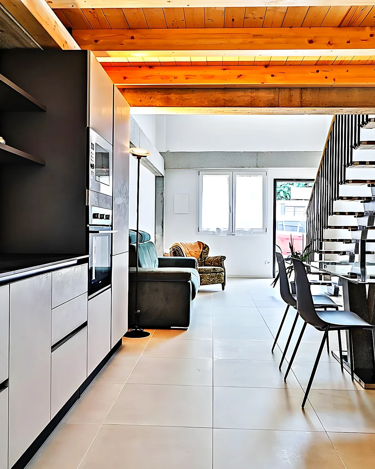 Cocina blanca y negra con la escalera del dúplex al fondo, en el barrio de Molí de Vent, Vilanova