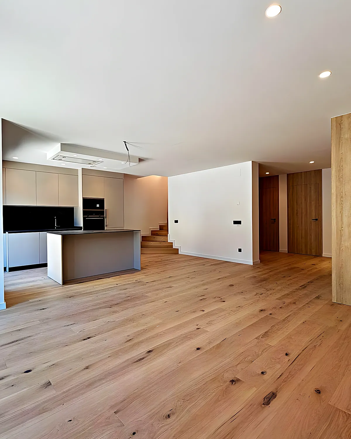 Salón con cocina abierta y carpintería de madera clara tras una reforma integral en Vilanova i la Geltrú