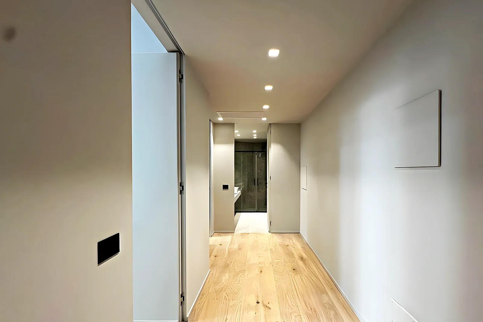 Pasillo con parquet y luz natural al fondo en un piso reformado integralmente en Vilanova i la Geltrú