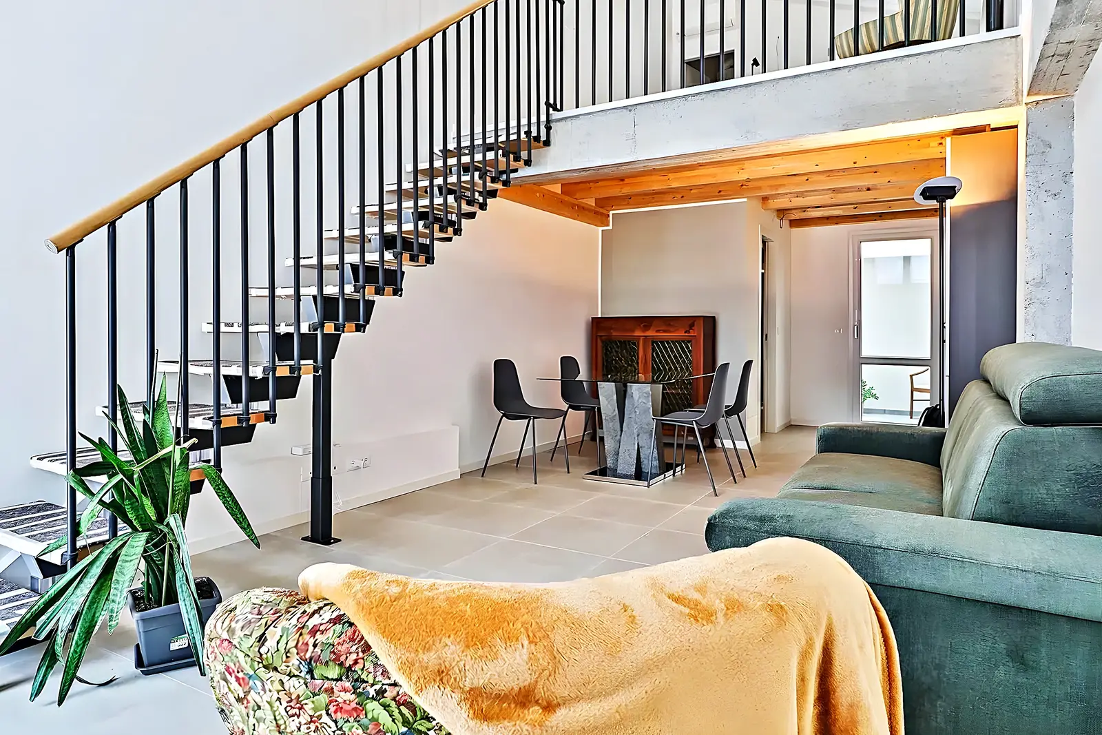 Salón de un dúplex reformado por Reformas Vilanoví con escalera metálica, en Vilanova i la Geltrú